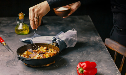 Rustic Cooking. A Woman sprinkles salt fries. Country style.