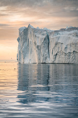 Iceberg at sunset. Nature and landscapes of Greenland. Disko bay. West Greenland. Summer Midnight Sun and icebergs. Big blue ice in icefjord. Affected by climate change and global warming. © Mathias