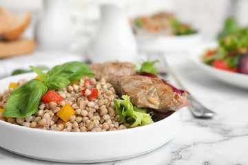 Tasty buckwheat porridge with meat on white marble table