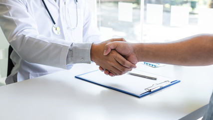 Doctor and patient shaking hands after a good and successful treatment in the hospital, healthcare and assistance concept