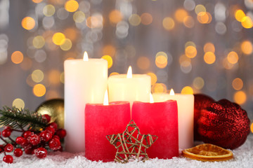 Christmas candles with decorative star, red berries and baubles on blurred background