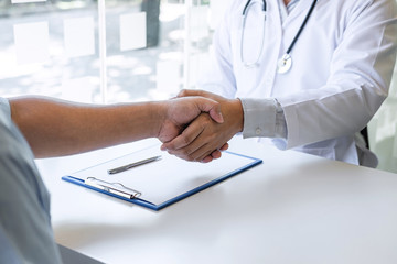 Doctor and patient shaking hands after a good and successful treatment in the hospital, healthcare and assistance concept