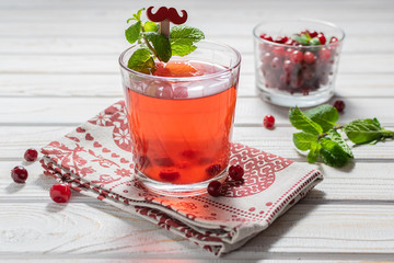 A glass of organic homemade cranberry tea with mint on the table close up. Traditional winter vitamin tea for flu and cold prophylaxis. 