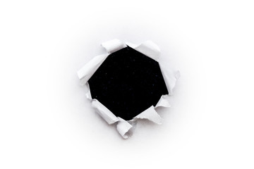 A round hole in white paper with torn edges isolated close-up with a black background inside with colorful space stars in the universe. A hole in paper with a view of the cosmos of the universe.
