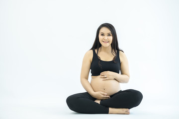 pregnancy, rest, people and expectation concept - happy pregnant woman sitting on bed and touching her belly at home