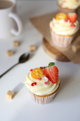 cupcake with cream cheese decorated with strawberries on a white background.