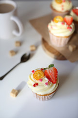 cupcake with cream cheese decorated with strawberries on a white background.