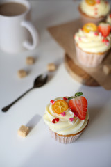 cupcake with cream cheese decorated with strawberries on a white background.
