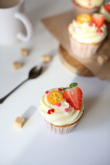 cupcake with cream cheese decorated with strawberries on a white background.