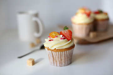cupcake with cream cheese decorated with strawberries on a white background.