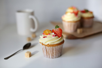 cupcake with cream cheese decorated with strawberries on a white background.
