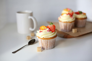 cupcake with cream cheese decorated with strawberries on a white background.