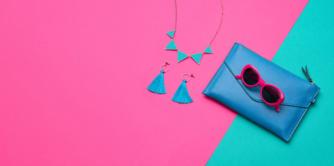 Fashion party girl layout Flat lay. Minimal. Woman Essentials accessories. Trendy Clutch, sunglasses, earrings. Coloful purple green Set. Creative pop art concept, vibrant fashionable color. Banner