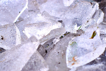 Ice fragments on frozen lake water level. The ice broken into shinning jagged pieces. Dark natural backlight
