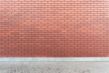 Wall red brick texture with an asphalt road. Urban style mockup background. Modern new brickwall on a street.