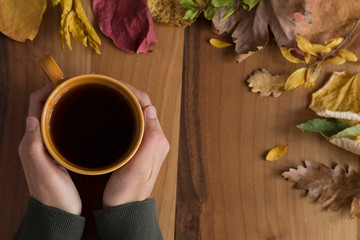 tea and autumn leaves on the wooden background.