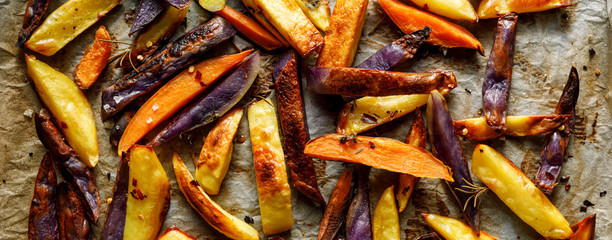 French fries,  baked fries from different types and colors of potatoes sprinkled with herbs and spices on a baking paper, top view
