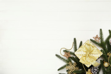 Gift box with ornaments and fir tree branches on white wooden table