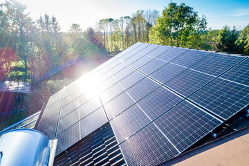 Solar panels and sunlight reflextions on the roof against blue sky background. Concept clean power...