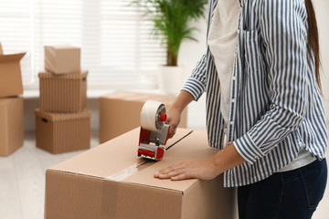 Fototapeta na wymiar Woman packing cardboard box indoors, closeup. Moving day