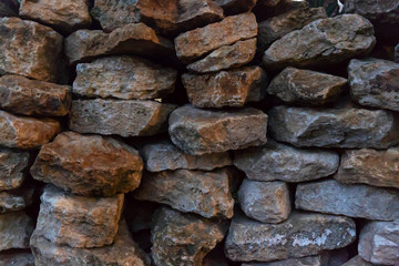 Background image of a stone wall made of natural gray and brown stone on dry.