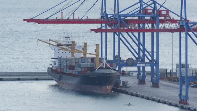 Harbor cranes loading containers on a ship before sailing