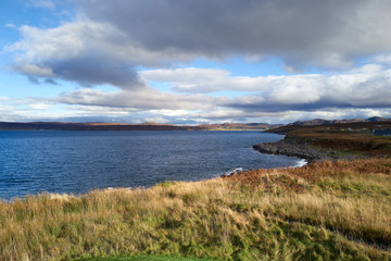 Views from the waters edge of Loch Gairloch with distant views of the small town of Gairloch on a sunny winters day.