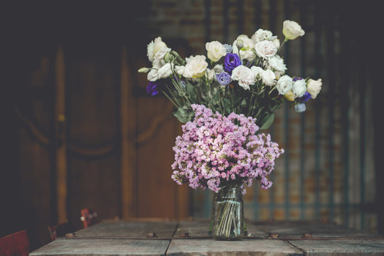 A bouquet of purple flowers in a glass vase on a wooden floor boards of old vintage.