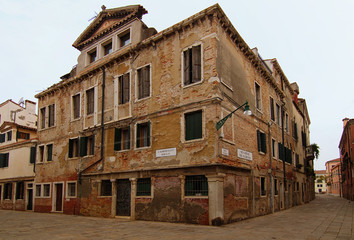 Wide angle landscape view of street in Venice city. Non-tourist part of the city. Typical street corner of the medieval city. Ancient brick residential building with cobblestone street. Venice, Italy