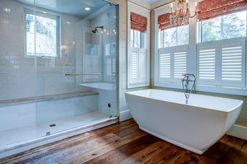 Beautiful luxury bathroom with large white tub and white tile walk in shower.