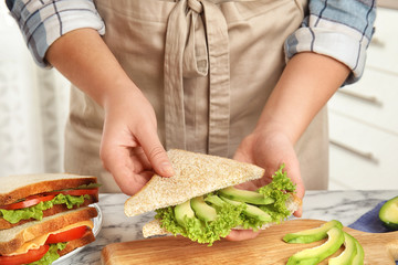 Woman making tasty sandwich at white marble table, closeup