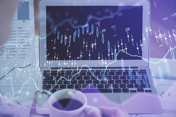 Stock market graph on background with desk and personal computer. Multi exposure. Concept of financial analysis.