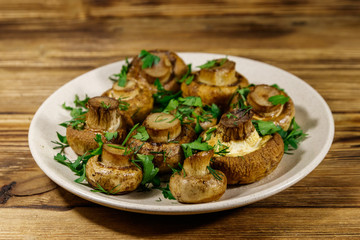 Baked mushrooms in plate on wooden table