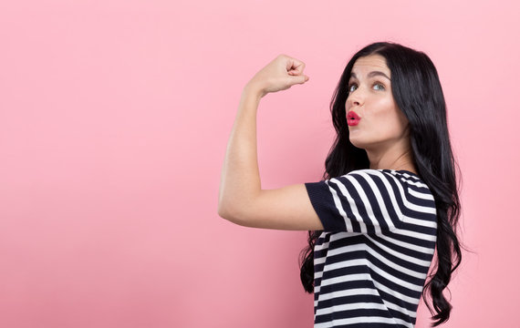 Powerful young woman in a success pose on a pink background