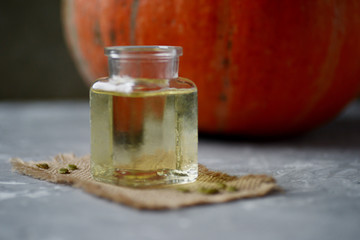 orange pumpkin and bottle with pumpkin oil on board.