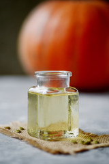orange pumpkin and bottle with pumpkin oil on board.