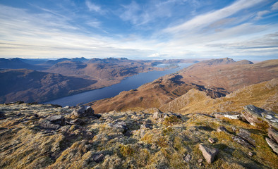 Views of Loch Maree and Flowerdale Forest in the distance from a frosty rocky summit of Slioch in the Scottish Highlands on a sunny winters day.
