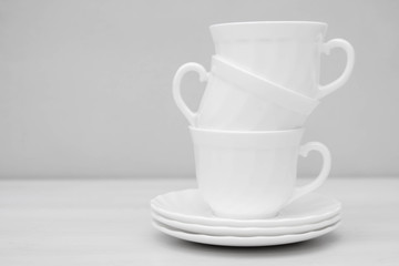 White ceramic cups with saucers on white table. Space for text