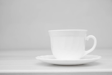 White ceramic cup with saucers on white table. Space for text
