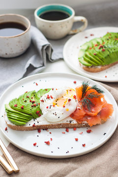 Toast with cream fresh, smoked salmon, poached egg and sliced avocado, and two cups of coffee. 