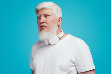 Pensive albino man with headphones on blue background