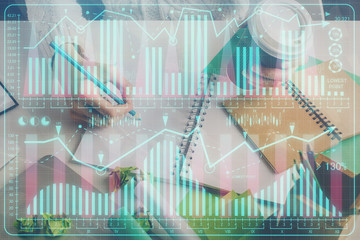 Financial forex graph displayed on hands taking notes background. Concept of research. Multi...