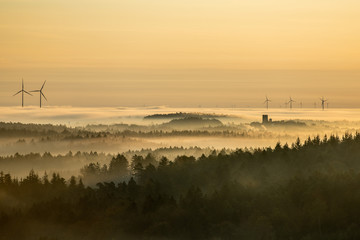 Fototapeta na wymiar Windkraftanlagen am Horizont im Morgenrot bei Nebel