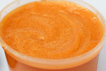 Body scrub in a plastic container. Orange scrub with cane sugar and mango.