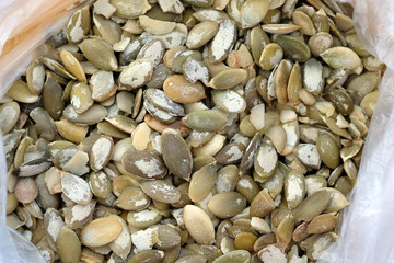 Green pumpkin seeds in a bag. Purified raw pumpkin seeds view from above.