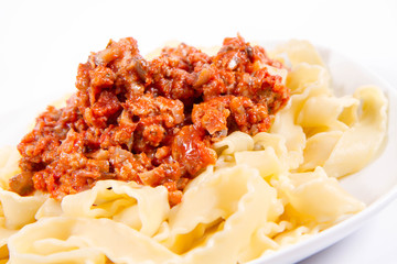 Reginette pasta with bolognese sauce on a plate on a white background