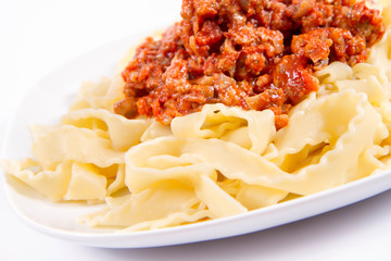 Reginette pasta with bolognese sauce on a plate on a white background