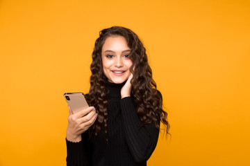 Happy model posing with phone in the yellow background