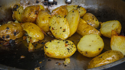 Delicious fried potatoes with peel lies in a large cast-iron pan. Dish of potato cooked in the open air.