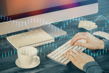 Multi exposure of graph with man typing on computer in office on background. Concept of hard work.